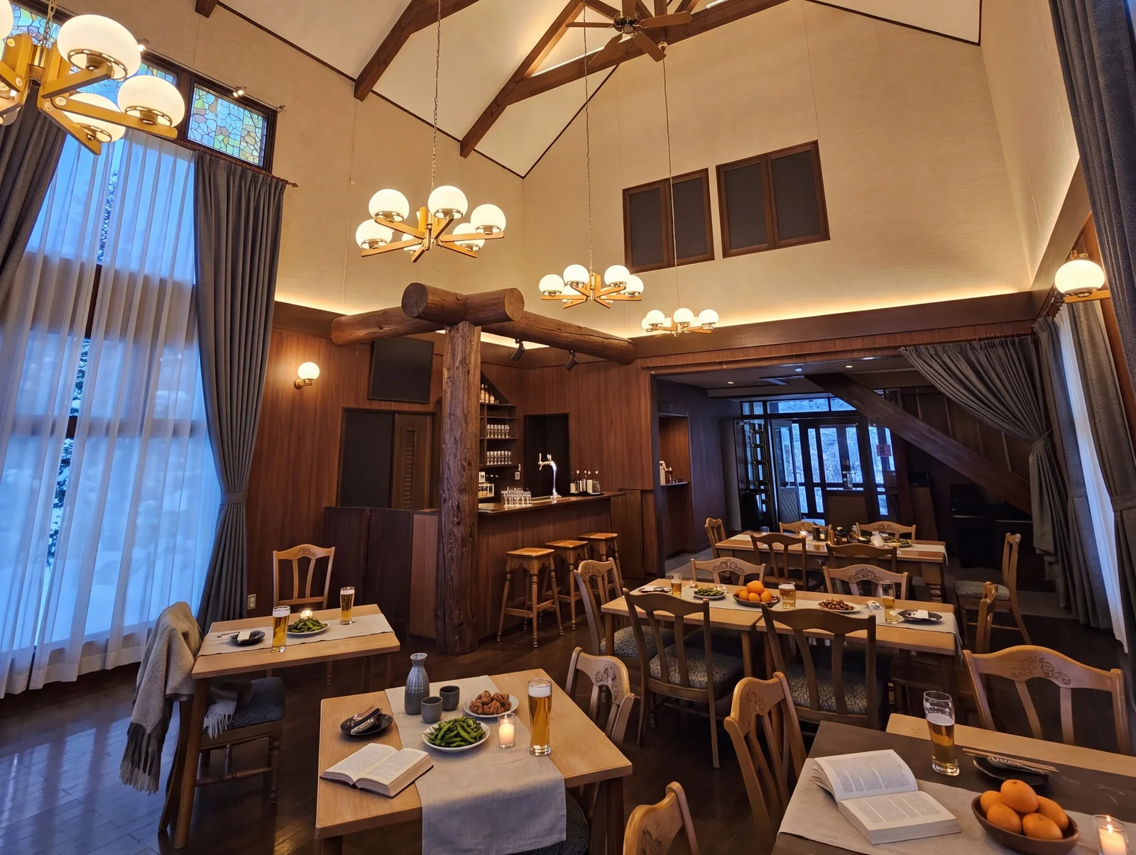 The dining room at dusk: globe chandeliers glowing under the timber trusses